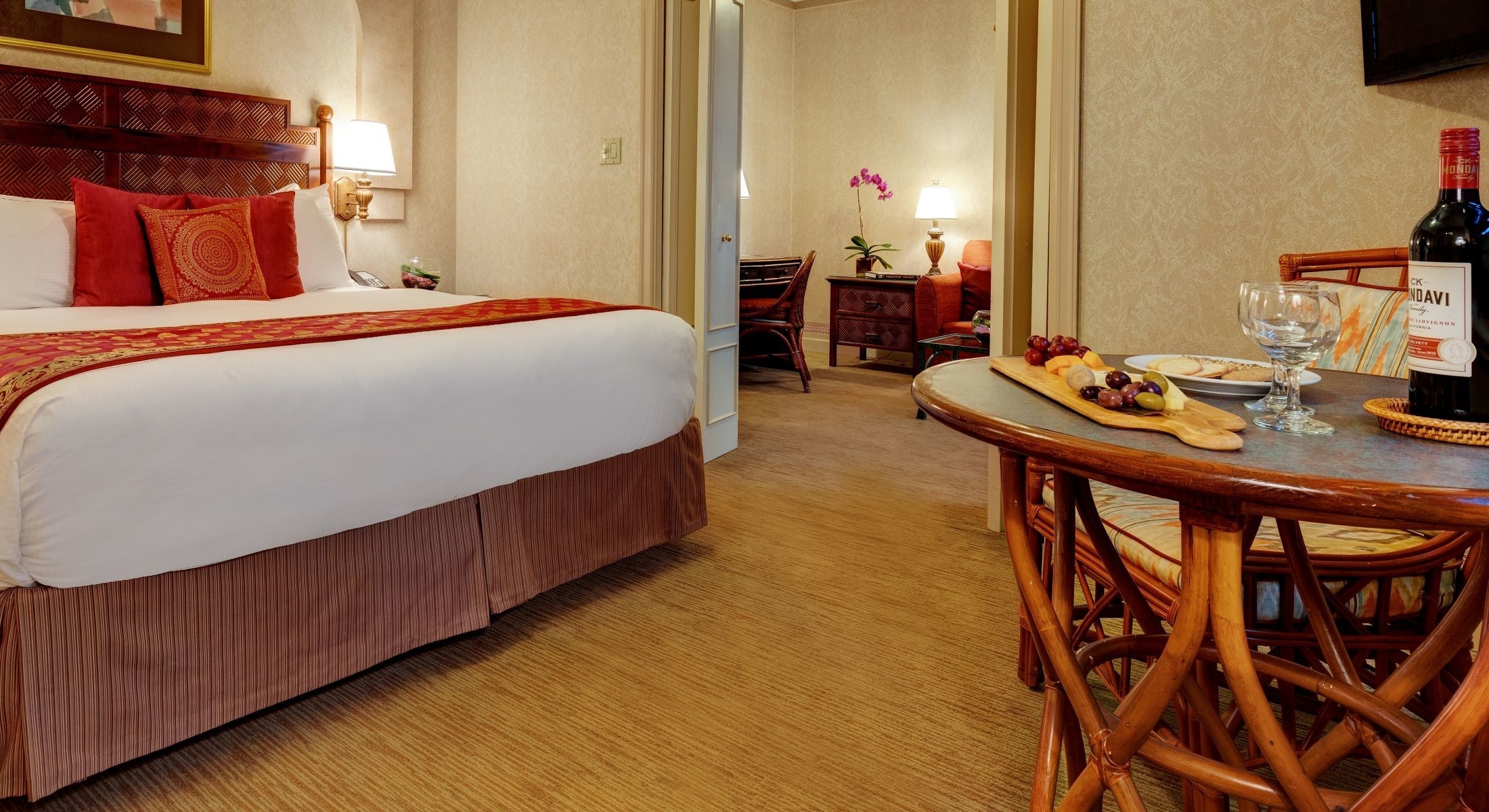 A hotel room with a king-sized bed, a small dining table, and a TV